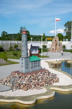 toy lighthouse, blue toy lighthouse and yellow sailboat with sand beach background