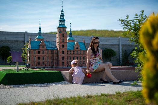 Happy mother and daughter in the park. Beauty nature scene with family outdoor lifestyle. Happy family resting together on the green grass, having fun outdoor. Happiness and harmony in family life.