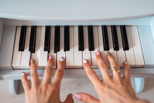 beautiful baby girl playing toy piano in light room.