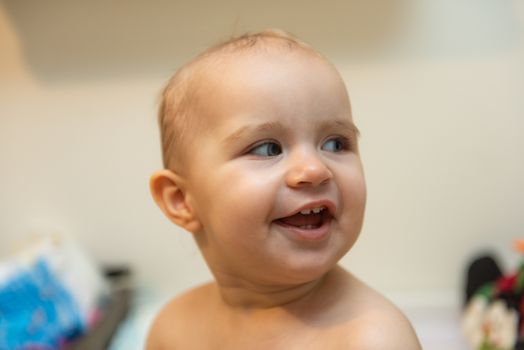 Adorable baby girl sitting under a hooded towel after bath.