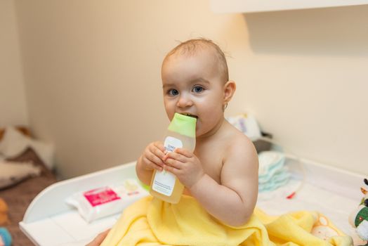 Adorable baby girl sitting under a hooded towel after bath.