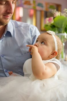 Baby girl 1 year old eating birthday cake in room. Birthday party. Childhood.