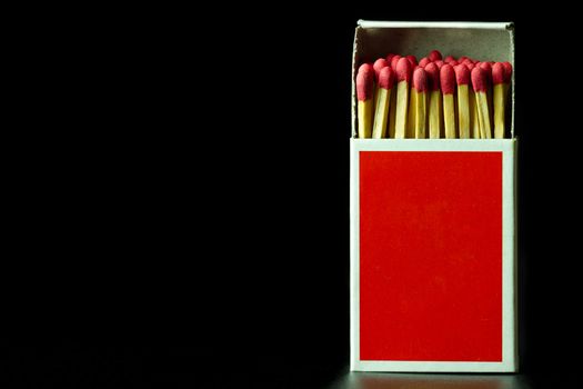 Matches stick in red paper box on black background. Closeup and copy space.