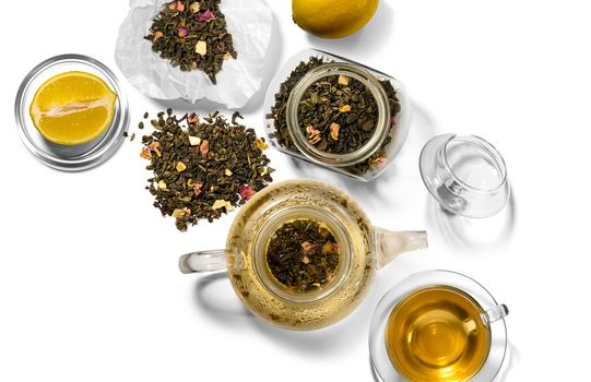 Tea, teapot, spoon and lemon on a white background.