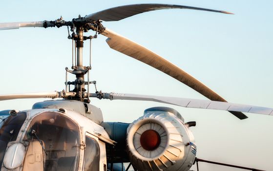 engine and propeller blades of an old vintage helicopter against a blue sky