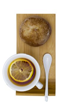 Bun and cup with tea on a wooden tray