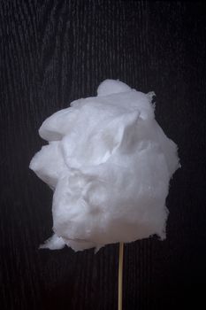 White cotton candy on a stick on a black background