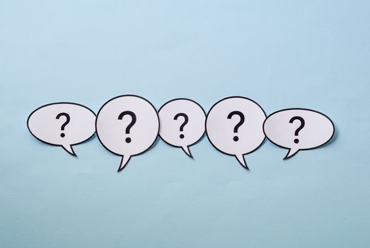 Line of question marks in speech bubbles of assorted shapes over a blue background with copy space above and below