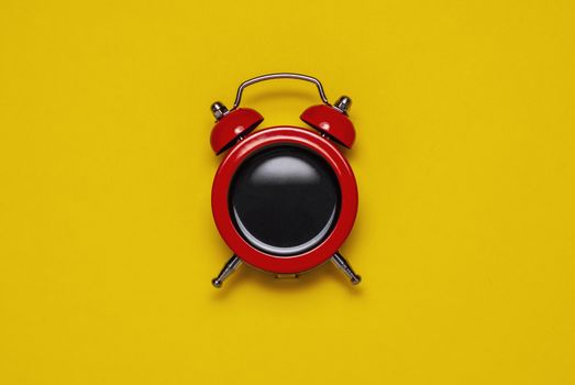 Red coffee alarm clock with bells centered over a yellow background viewed from above with copy space
