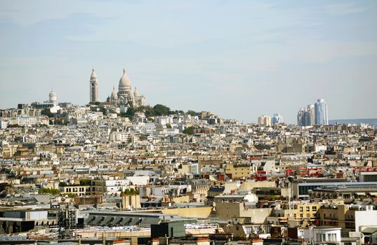 Sacre Coeur basilica and Chateau d'eau Montmartre on the hill, seen across the densely-built Paris cityscape from the top of the Arc de Triomphe