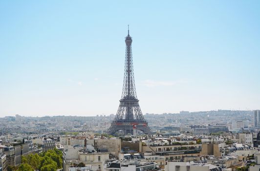 Eiffel Tower rises above the city of Paris, seen across the rooftops from the Arc de Triomphe