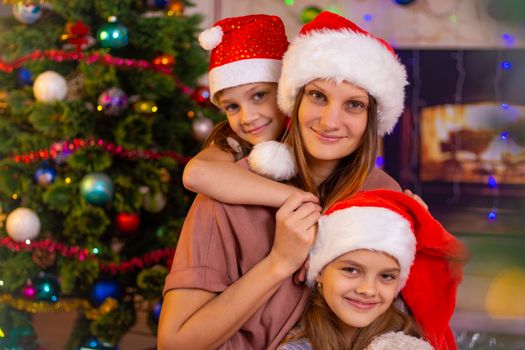 Mother and two daughters at the Christmas tree