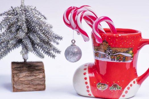 Christmas candy canes in a red cup in the background Christmas tree. New Year concept.Red and white candy canes in red cup