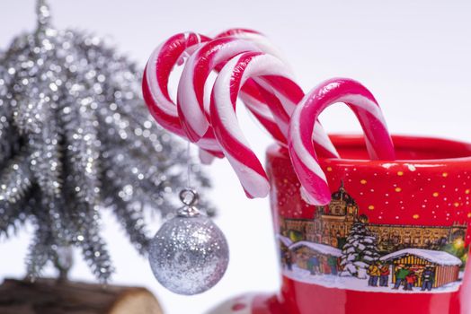 Concept of christmas drink on a white background.Red and white candy canes in red cup.