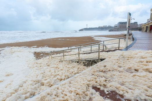 Foam on the Grande Plage beach and its quay during a storm, France