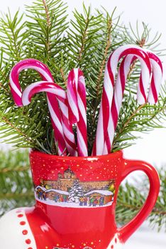 Christmas candy canes in a red cup in the background Christmas tree. New Year concept.Red and white candy canes in red cup