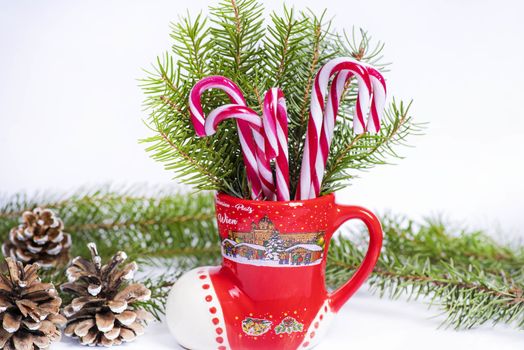 Christmas candy canes in a red cup in the background Christmas tree. New Year concept.Red and white candy canes in red cup