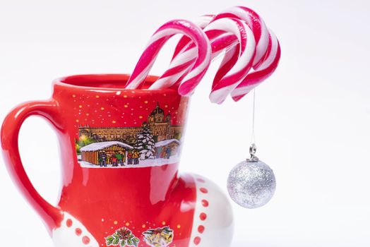 Concept of christmas drink on a white background.Red and white candy canes in red cup.