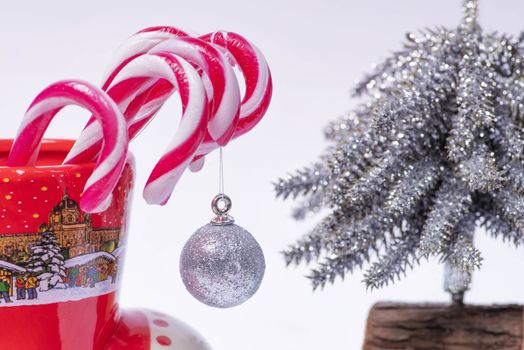 Christmas candy canes in a red cup in the background Christmas tree. New Year concept.Red and white candy canes in red cup