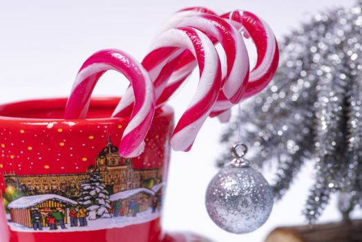 Christmas candy canes in a red cup in the background Christmas tree. New Year concept.Red and white candy canes in red cup