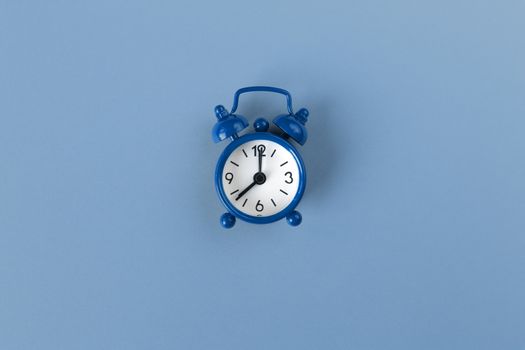 Small alarm clock on pastel background in Classic Blue colour, close-up, top view. Minimal retro style. Time management, Color of the year 2020 concept. Copy space for text. Horizontal orientation.