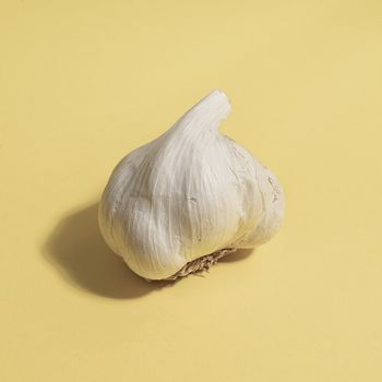 A garlic bulb on a yellow surface