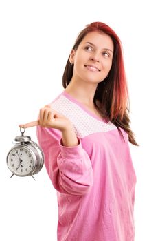 Early morning concept. Beautiful smiling young woman in pink pajamas holding an alarm clock looking up, isolated on white background.