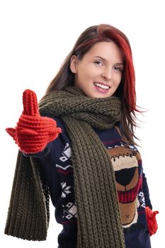 Beautiful young smiling woman in warm winter sweater, knitted scarf and mittens giving thumbs up, isolated on white background. Portrait of an attractive cheerful girl in warm winter clothes.