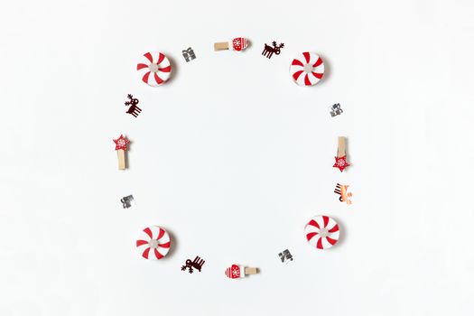 Simple Christmas composition. Round frame of clothespins, candy-bulbs, deer confetti and gifts on white background, copy space. Horizontal. Minimal style. Top view. For social media, greeting card.