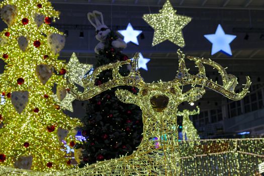 Bright festive Christmas illumination. Glowing figure of a deer against the background of a Christmas tree.