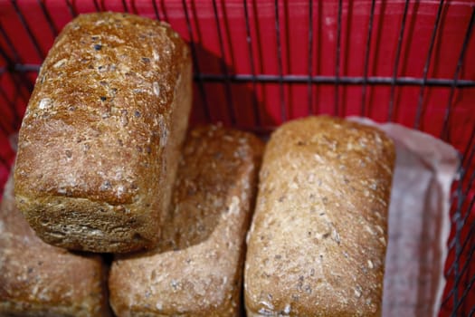 Delicious fresh baked with a ruddy crust bread lies in a metal basket on the counter of the grocery store.