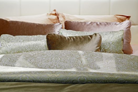 A cozy bed with soft pillows is shot close-up. Blurred background.