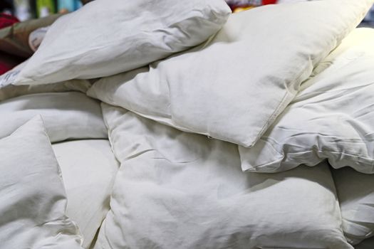 A lot of white soft down pillows lie on top of each other.