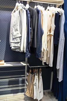 A number of different clothes hang on hangers in a modern blue closet. Convenient storage