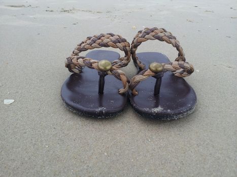 Women's sand-stained slippers on the beach