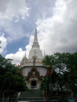 The white pagoda with cloudy sky and have a tree around.