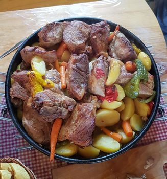 Traditional croatian dish Peka view, meat and vegetables in iron cover under warm glow