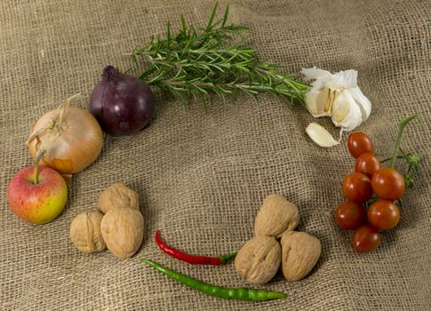 frame of different ingredients foods vegetables and herbs with space in the middel for text on jute background
