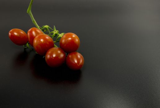 fresh red cherry tomatoes on black background