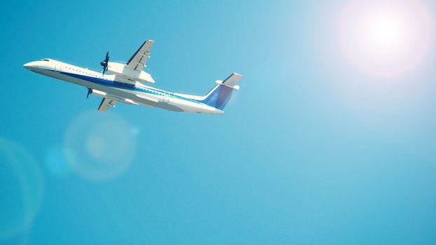 Airplane taking off to the blue sky from international airport runway in Sapporo Hokkaido Japan and have sun light flare to camera and shoot from uprisen or low angle view.