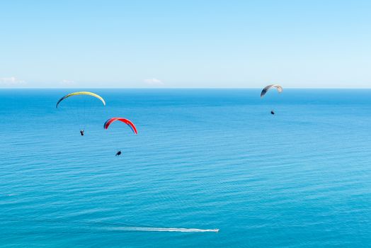 Three tandem paragliders above Sea Point after launch from Signal Hill in Cape Town in the Western Cape Province. Speedboats are visible below