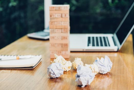 Business game wood block tower fail with paper crumpled on desk office