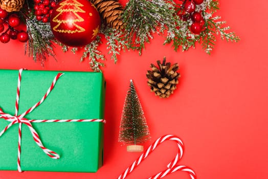 Christmas green gift box and decorations, fir tree branches on red background. Merry Christmas concept. With Copy space for text