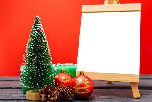 Christmas composition decorations, minimal green fir tree branches with snow and white chalkboard on red background. Merry Christmas concept. Copy space for text