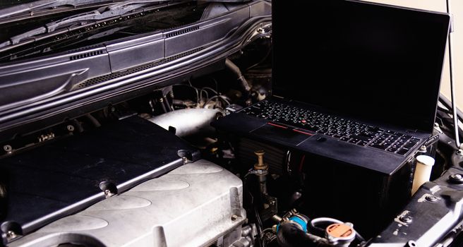 Laptop computer on car mechanic engine for service at workshop