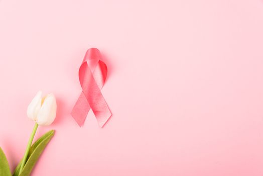 Breast cancer month concept, flat lay top view, pink ribbon and Tulip Flower on pink background with copy space for your text