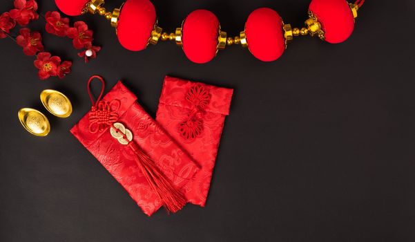 Chinese new year concept, flat lay top view, Happy Chinese new year with Red envelope and gold ingot (Character "FU" means fortune, blessing, wealth) on black background with copy space for your text