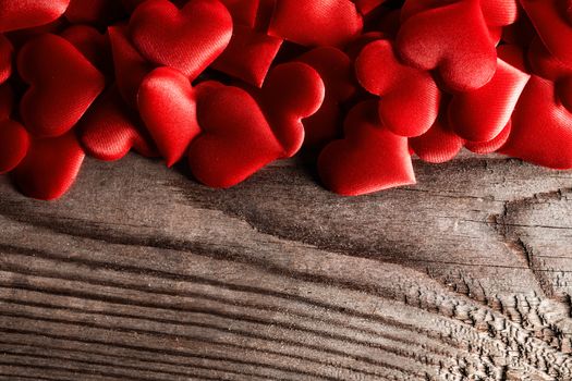 Valentine's day many red silk hearts on wooden background, love concept
