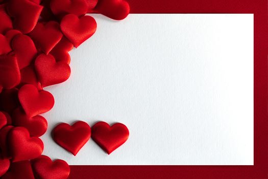 Valentine's day many red silk hearts background , border frame with white card with copy space, love concept