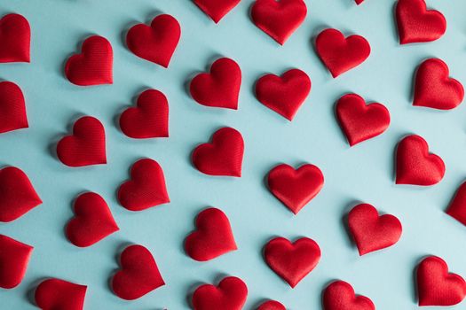 Valentine's day many red silk hearts on blue paper background, love concept